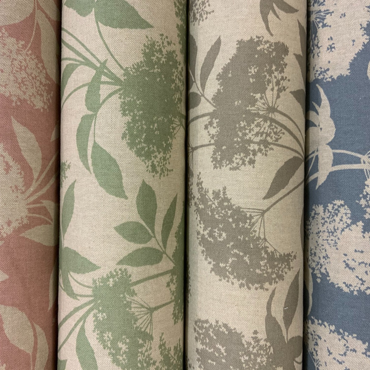 Five rolls of fabric with floral patterns in pink, green, gray, and blue.