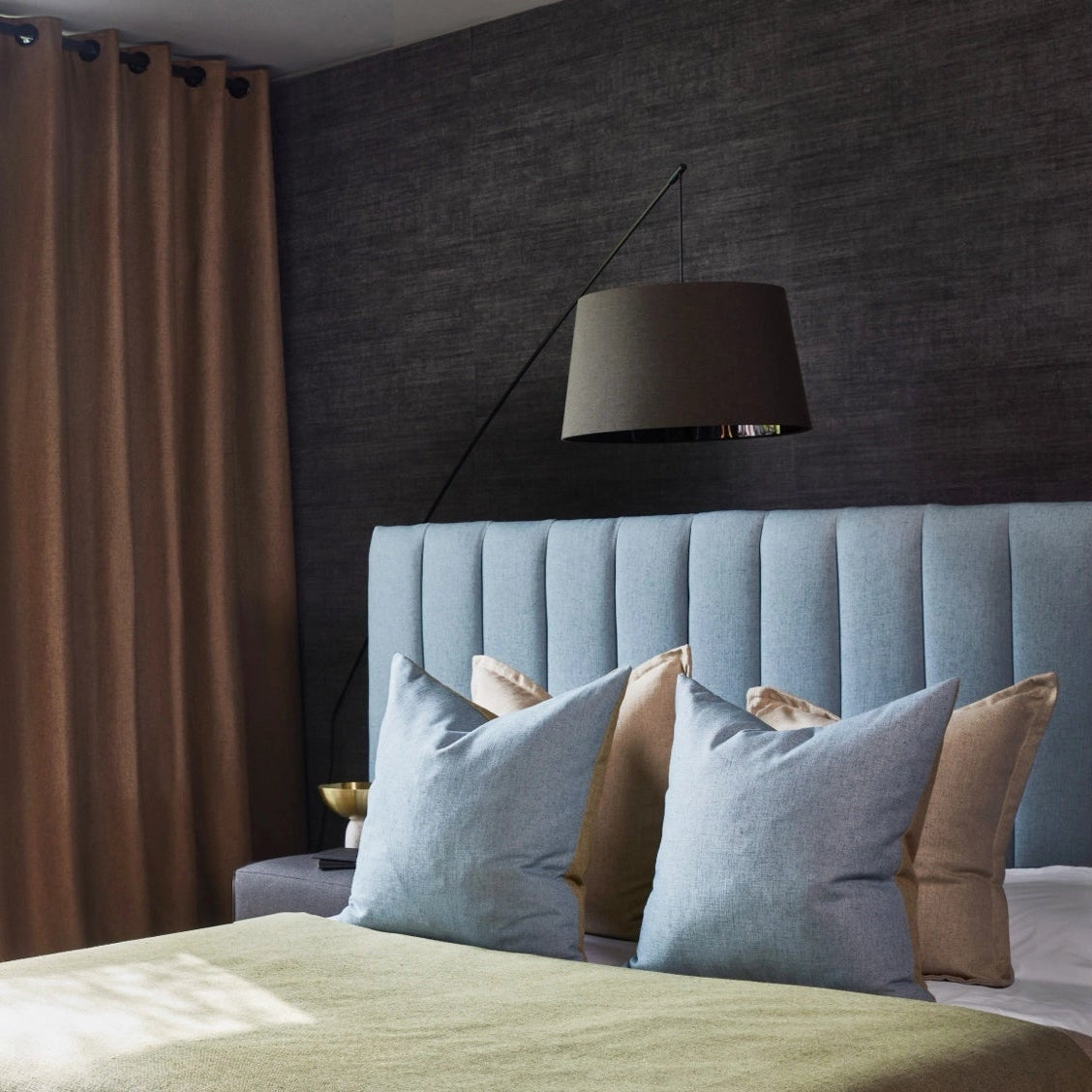 Modern bedroom with a bed, lamp, and large window with brown curtains.