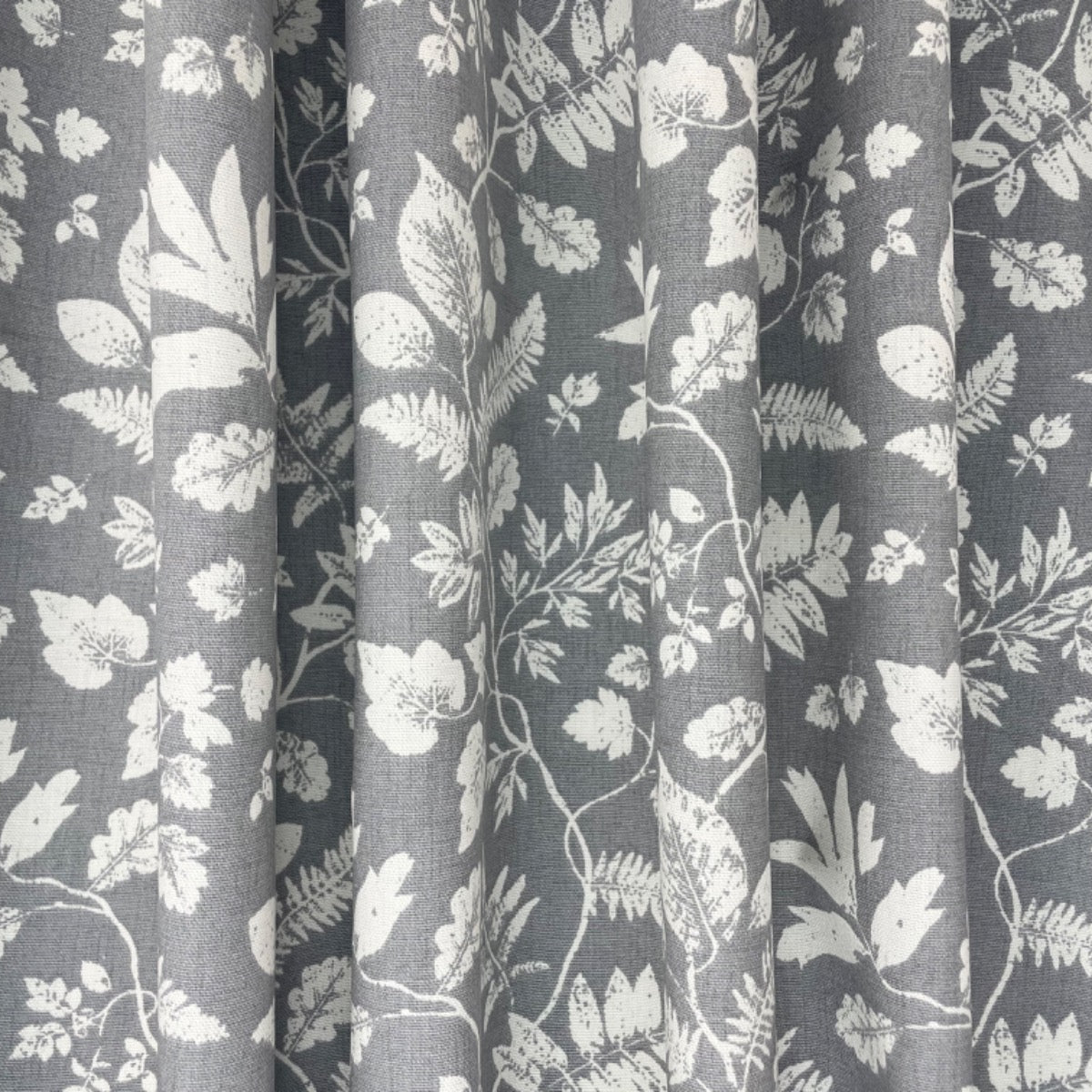 Clarke & Clarke floral print cotton curtain fabric grey background. Folded.