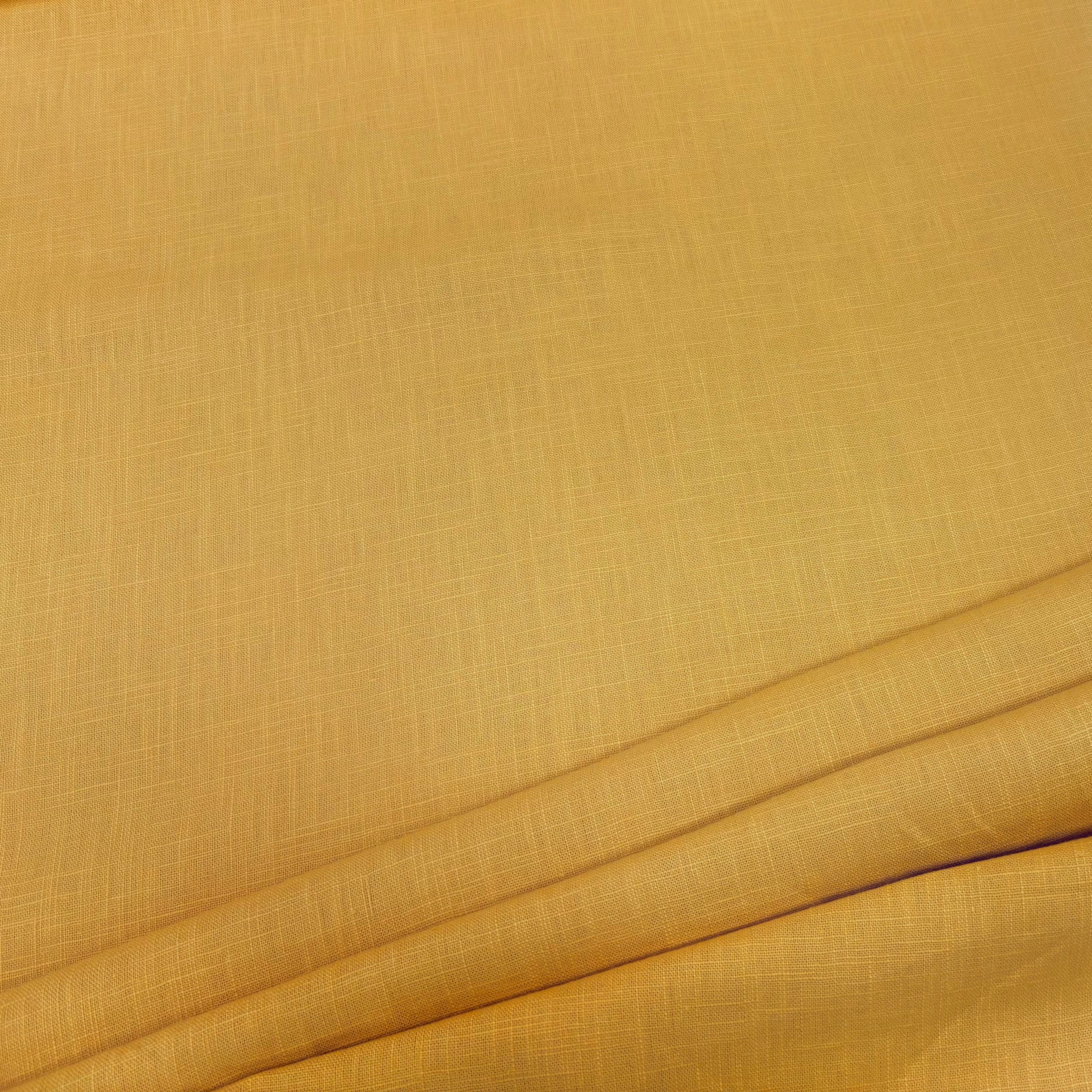 Close-up of mustard ramie linen dress fabric, highlighting its natural fibers, subtle weave pattern, and soft, slightly textured