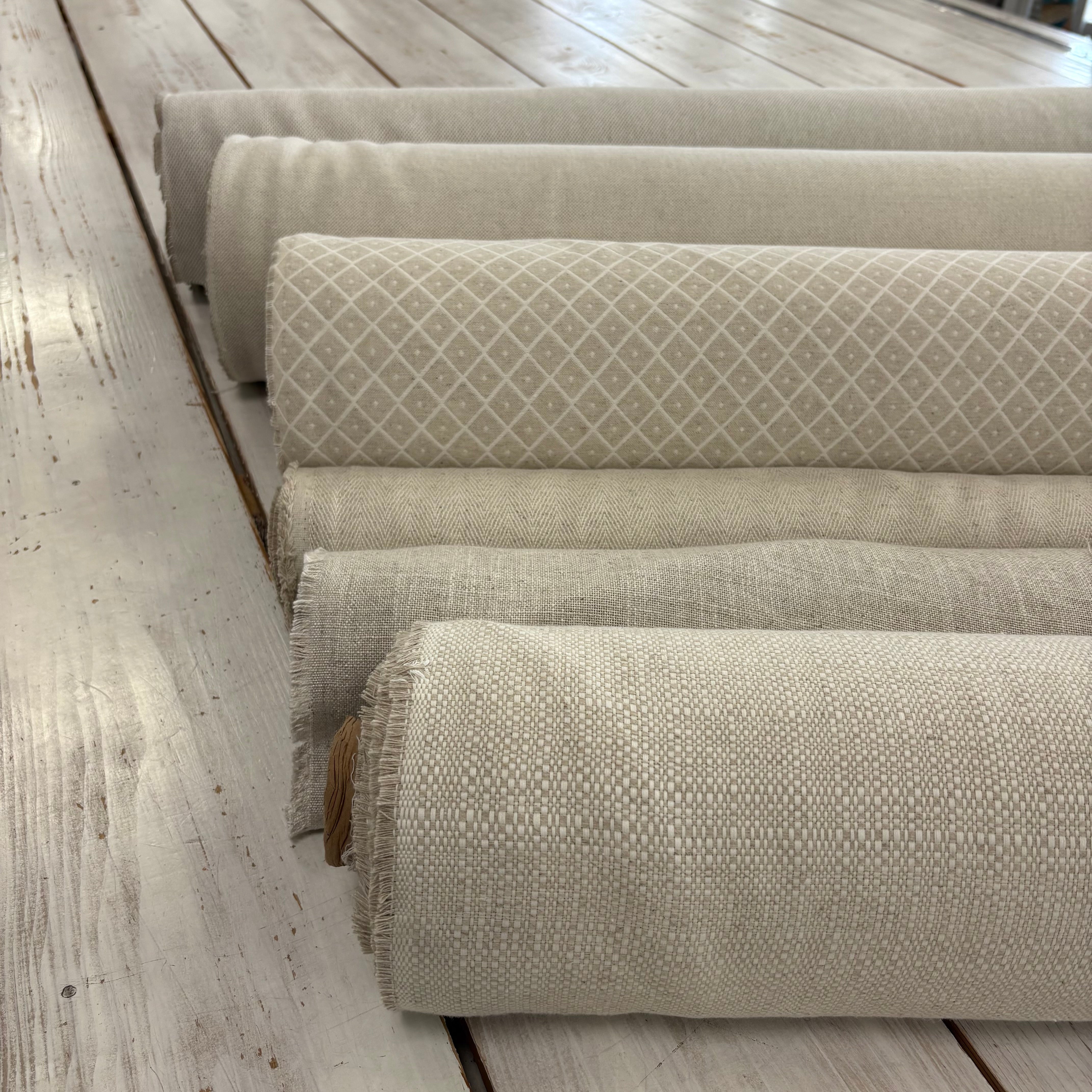 Five rolls of textured linen fabric in a neutral linen colour pallete