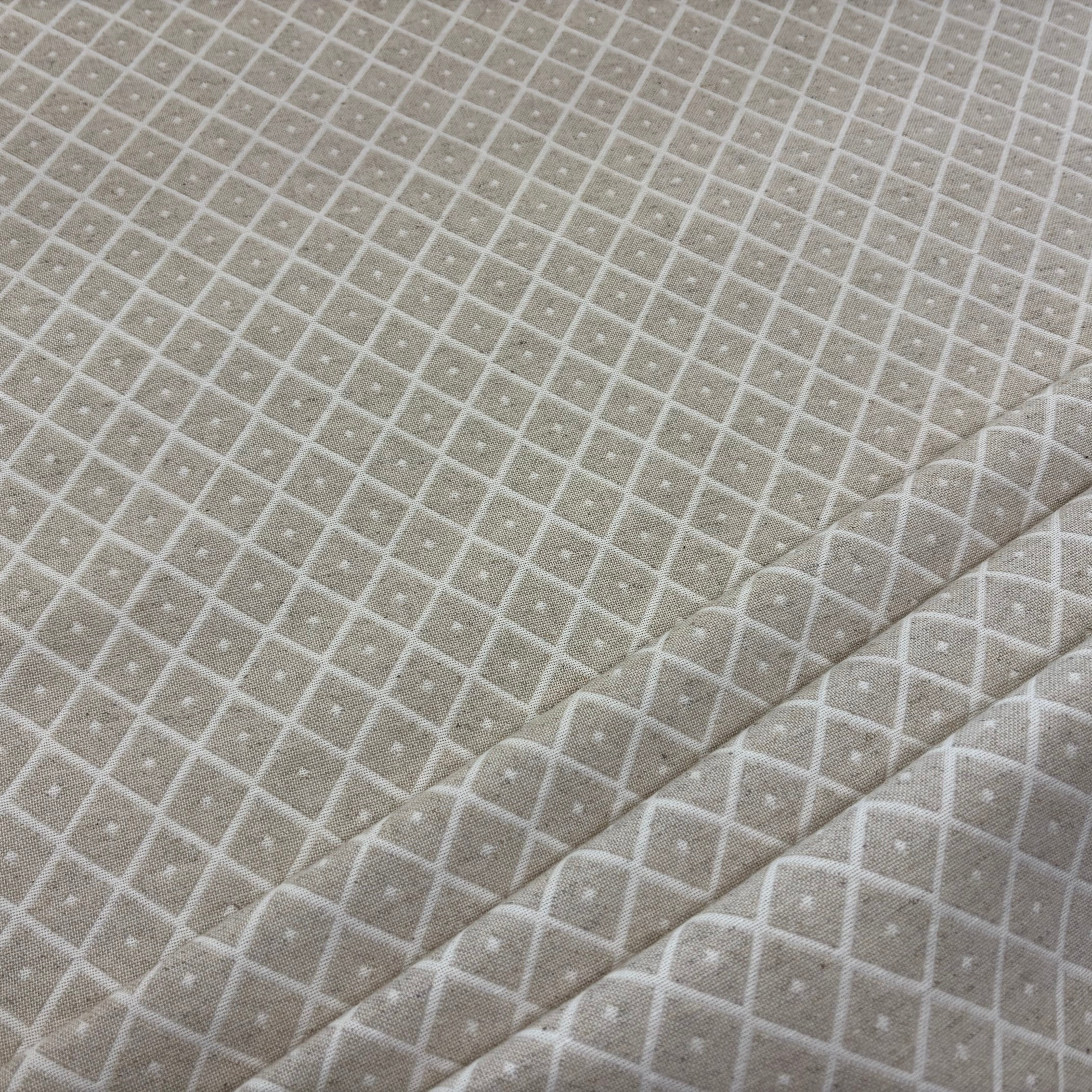 A close-up of a light linen coloured fabric with self patterned diamond weave