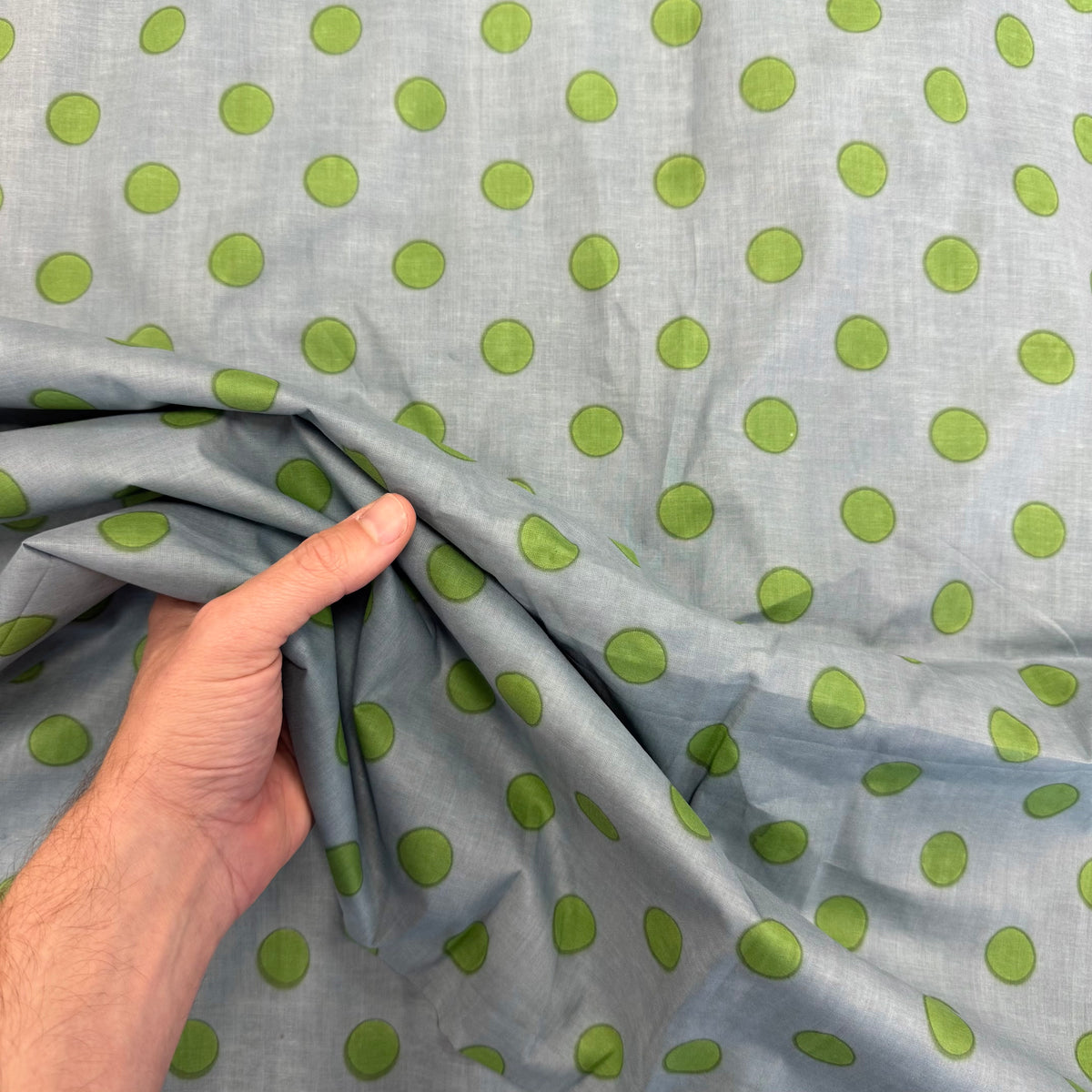 Mineral Blue Spotty Indian Print Cotton Fabric with hand for scale, lightweight 100gsm printed cotton for dressmaking, handmade gifts, crafts and soft furnishings, handcrafted using traditional Indian printing techniques.