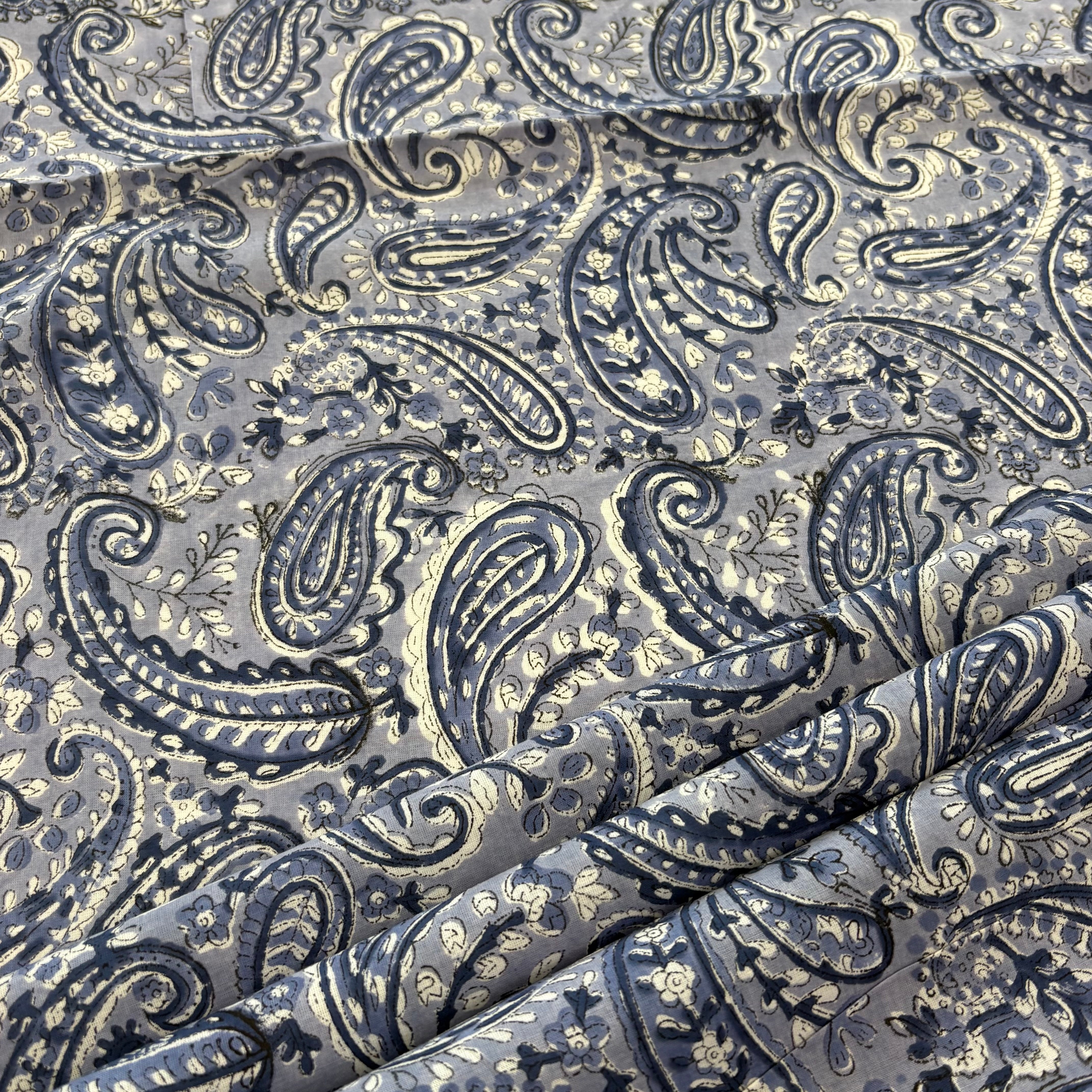 A close-up of draped fabric featuring an intricate paisley pattern in blue.