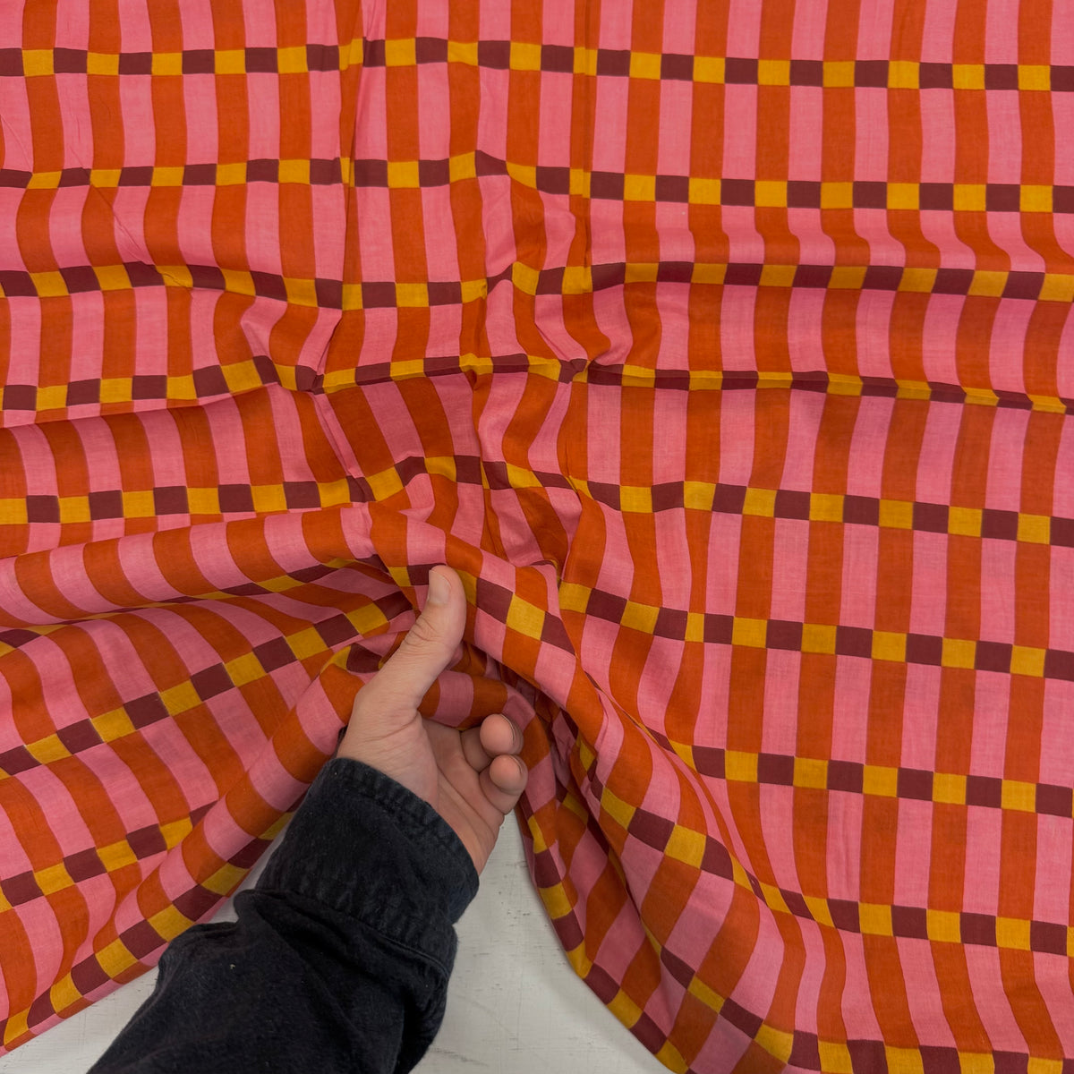 Pink Humbug Check Indian Block Print Cotton Fabric with hand for scale, lightweight 100gsm printed cotton for dressmaking, handmade gifts, crafts and soft furnishings, handcrafted using traditional Indian printing techniques.
