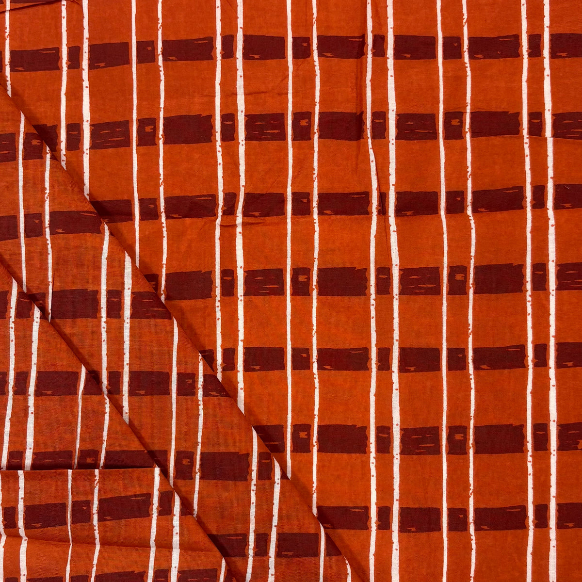 Rust Sketch Tartan Block Print Cotton Fabric, folded, lightweight soft cotton with a traditional handcrafted Indian tartan check pattern.