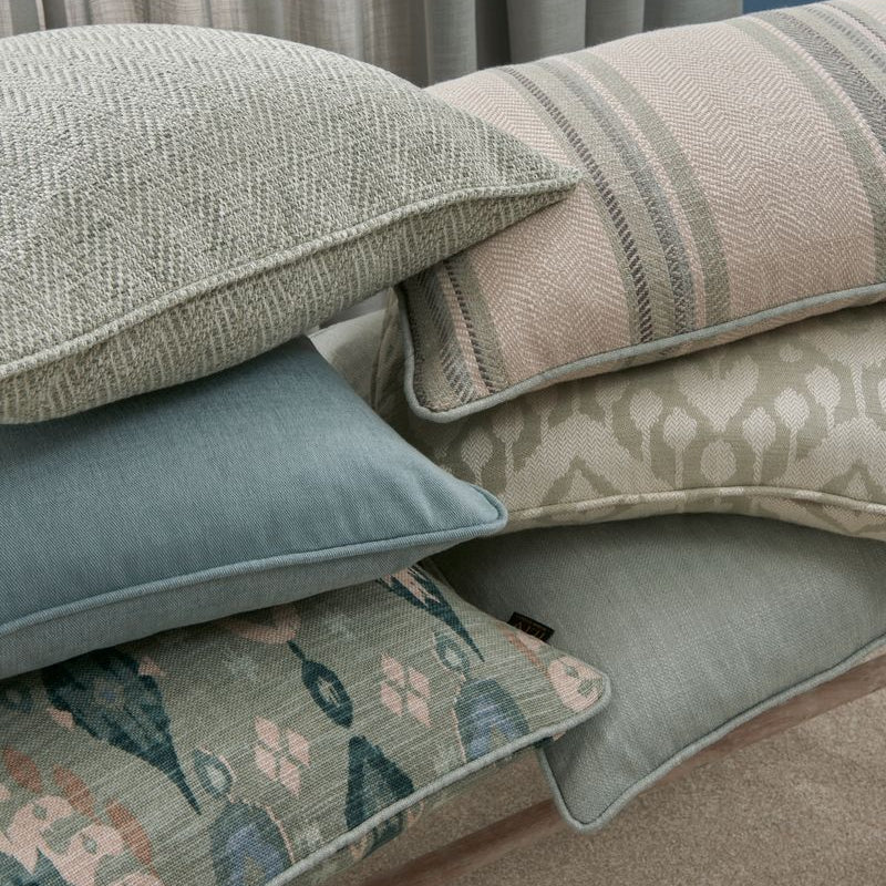 Stack of patterned cushions on a sofa with a neutral background