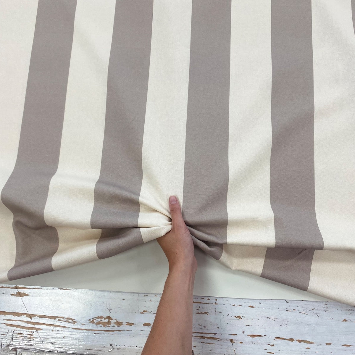 Bold Taupe Stripe fabric with hand for scale