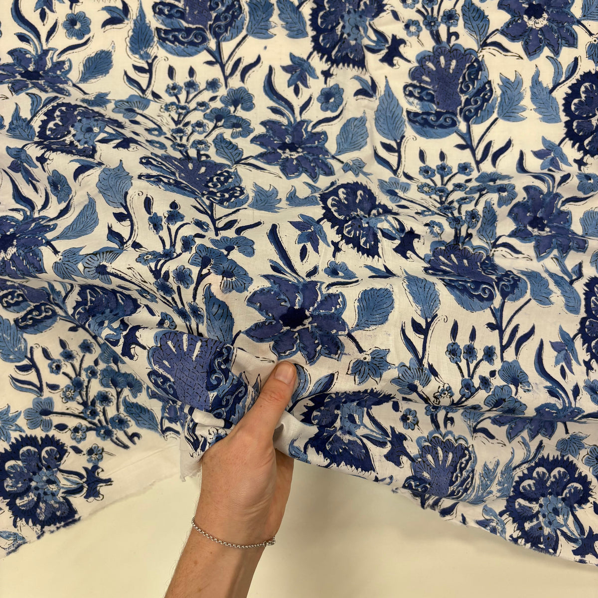 Trailing blooms Floral block Print Cotton Fabric, with hand for scale, lightweight, soft cotton fabric featuring a traditional handcrafted Indian block print floral pattern, perfect for dressmaking, quilting, crafts, handmade gifts and light home décor projects.