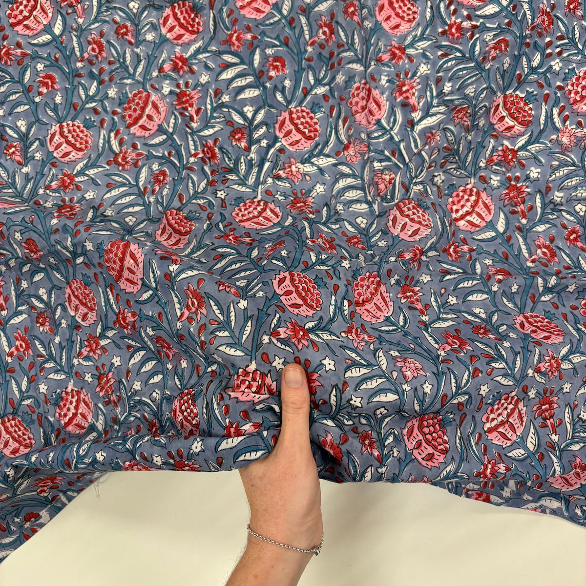 Winter Floral Indian Print Cotton Fabric, with hand for scale, lightweight, soft cotton fabric featuring a traditional handcrafted Indian block print floral pattern, perfect for dressmaking, quilting, crafts, handmade gifts and light home décor projects.