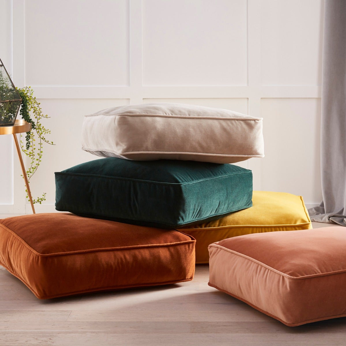 Stack of colorful cushions on a light wooden floor with a neutral background