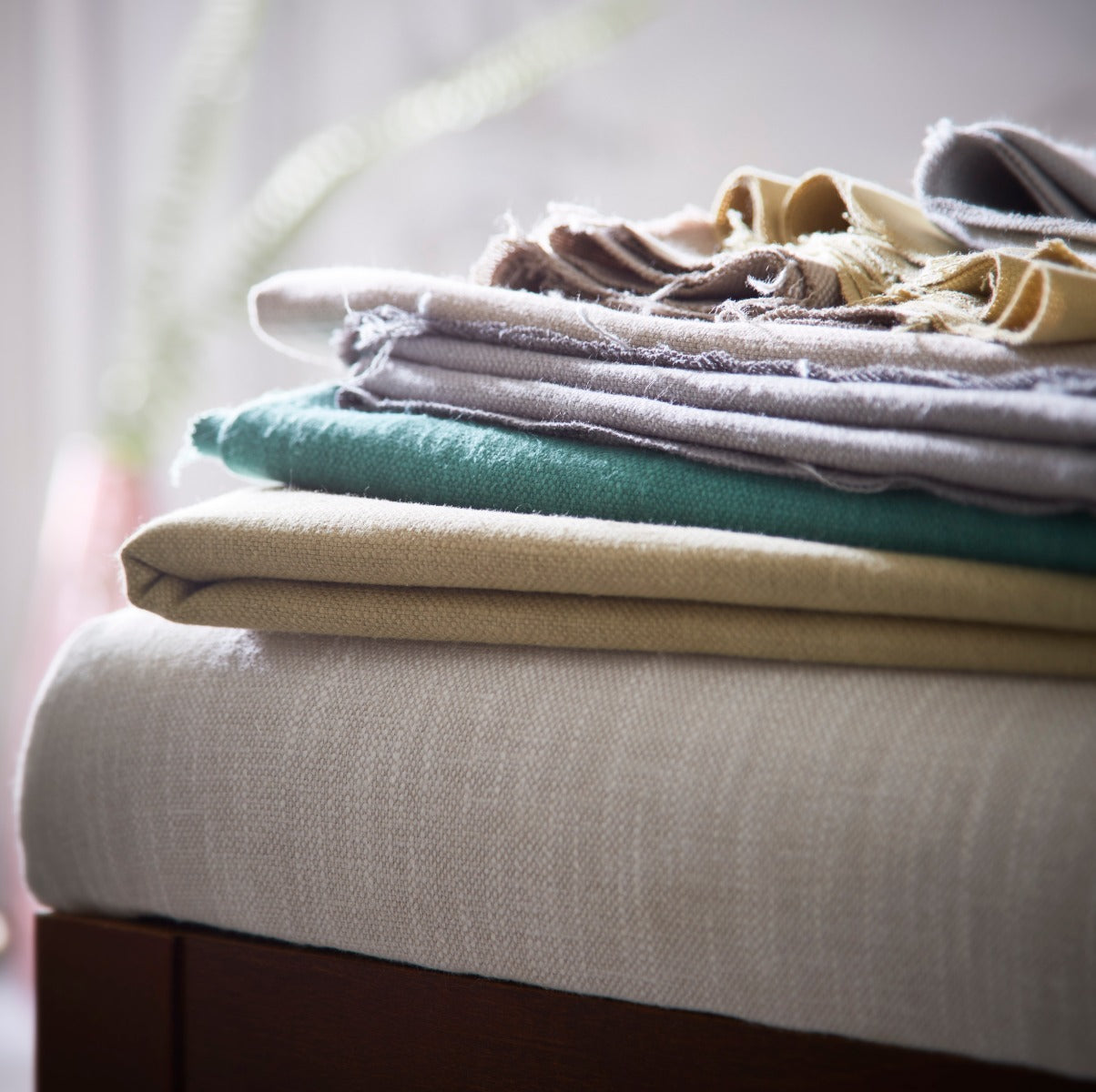 Stack of folded clothes on a bed with a blurred background