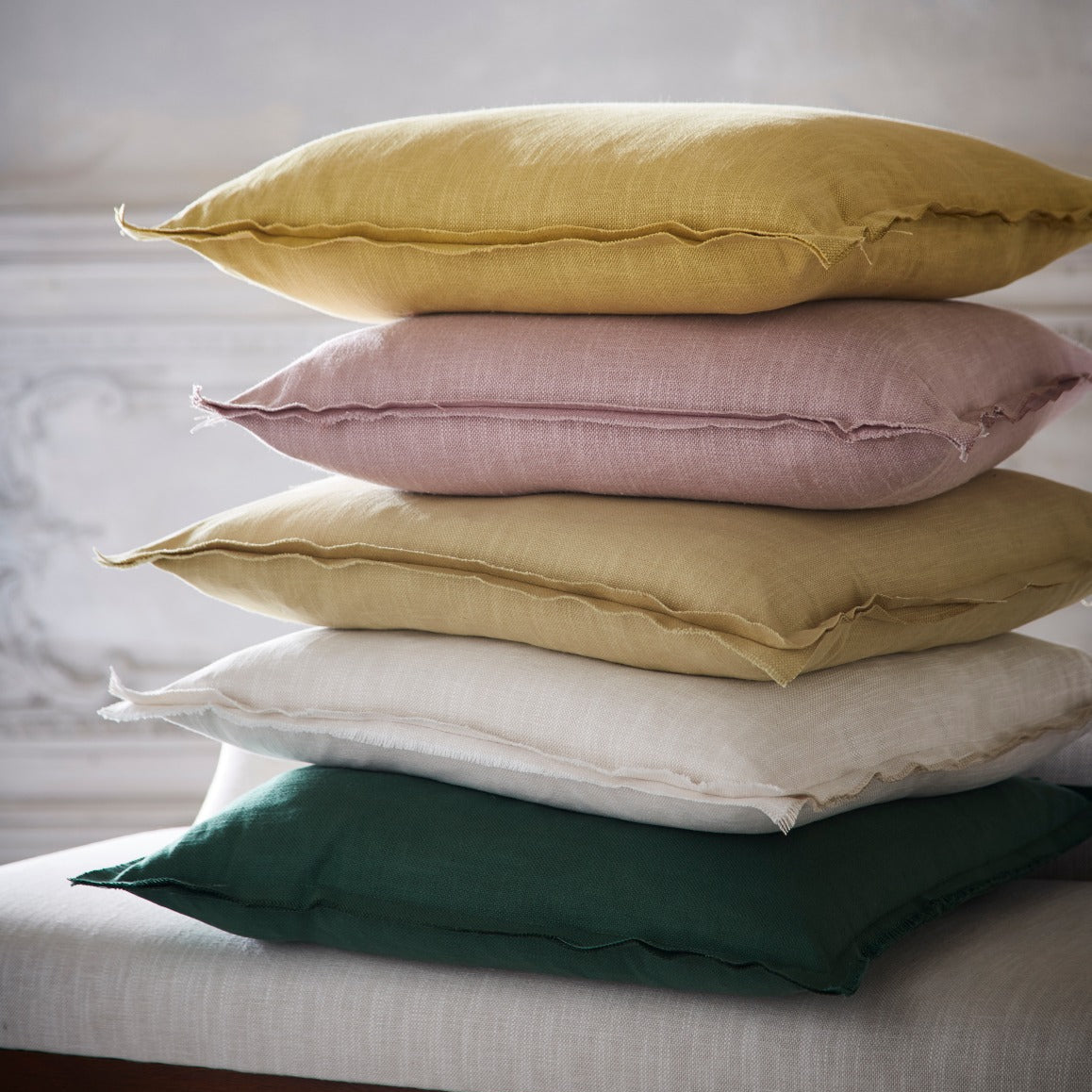 Stack of colorful pillows on a bed with a neutral background