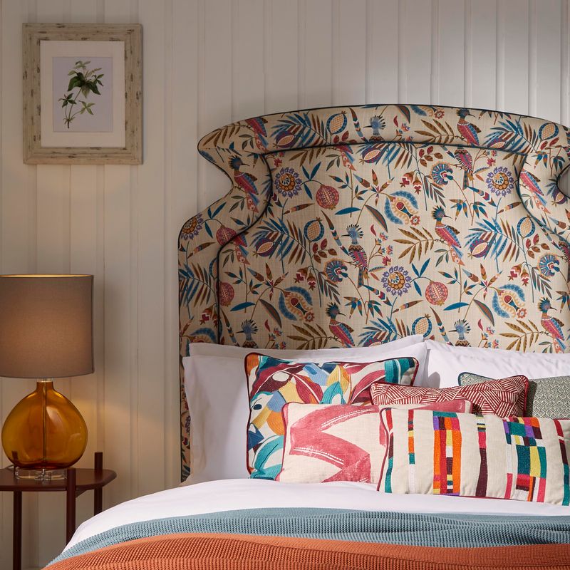 Bedroom with a floral-patterned headboard and colorful pillows on a bed.