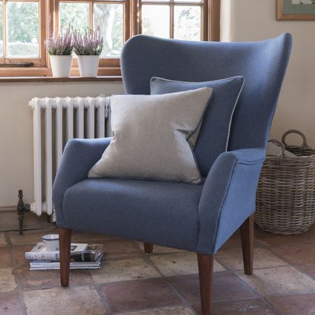 Blue armchair with cushions in a room with a radiator and window