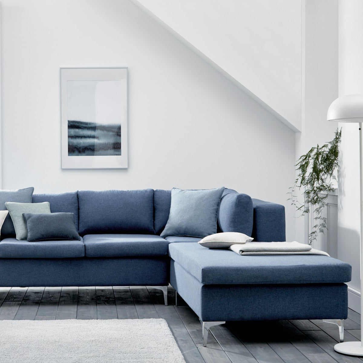 Blue sectional sofa in a modern living room with white walls and decor.