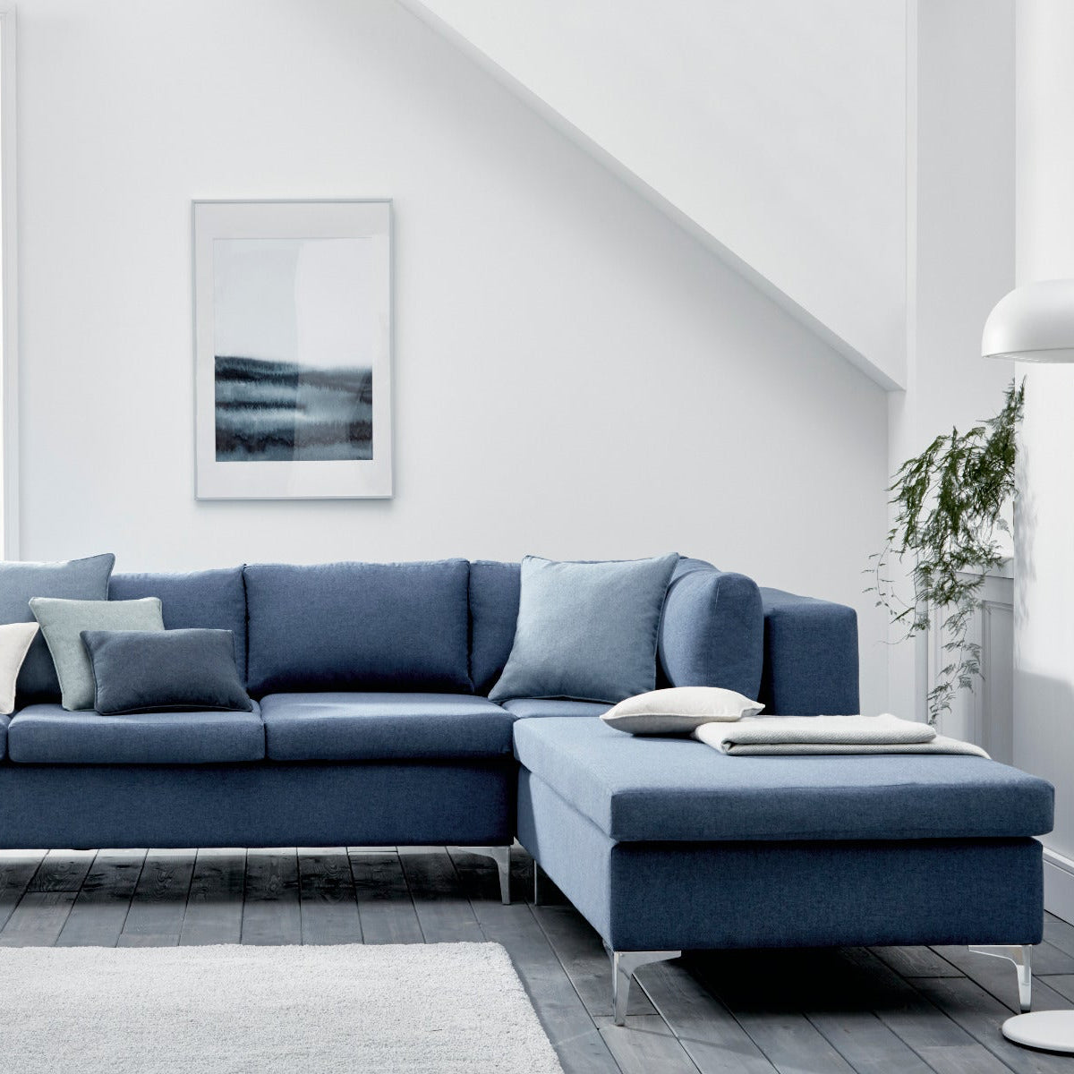 Blue sectional sofa in a modern living room with white walls and decor.