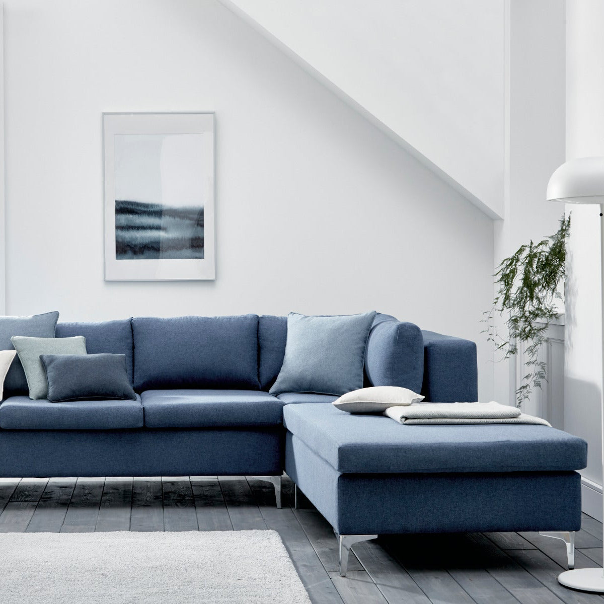 Blue sectional sofa in a modern living room with white walls and decor.
