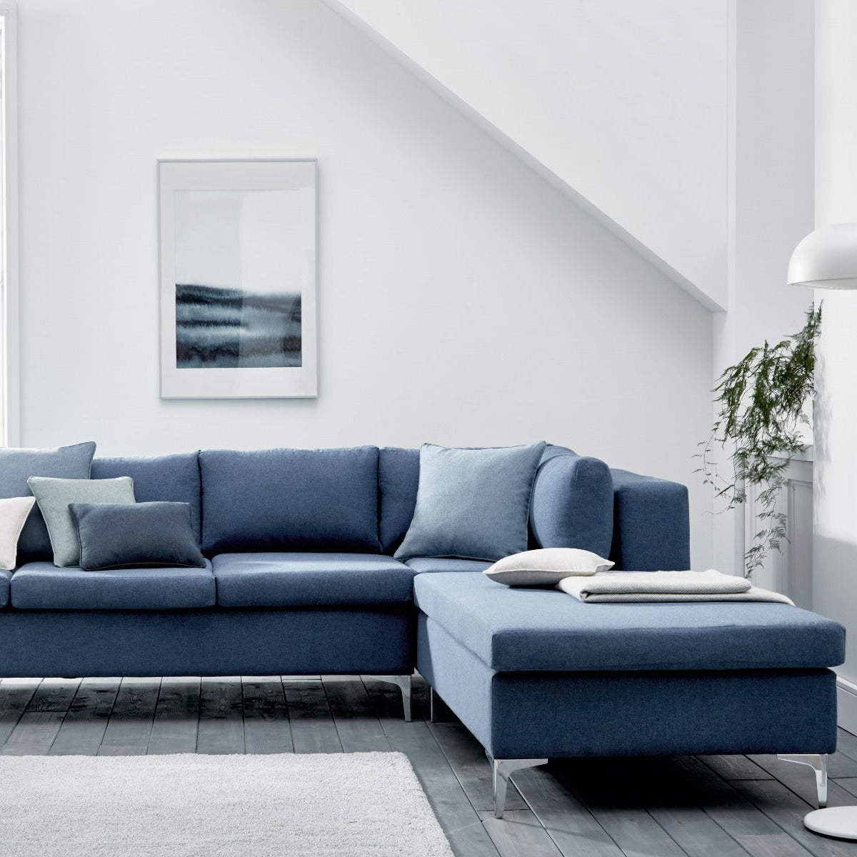 Blue sectional sofa in a modern living room with white walls and decor.