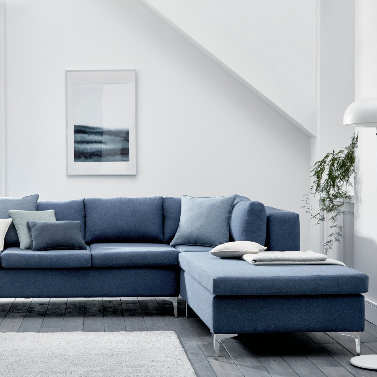 Blue sectional sofa in a modern living room with white walls and decor.