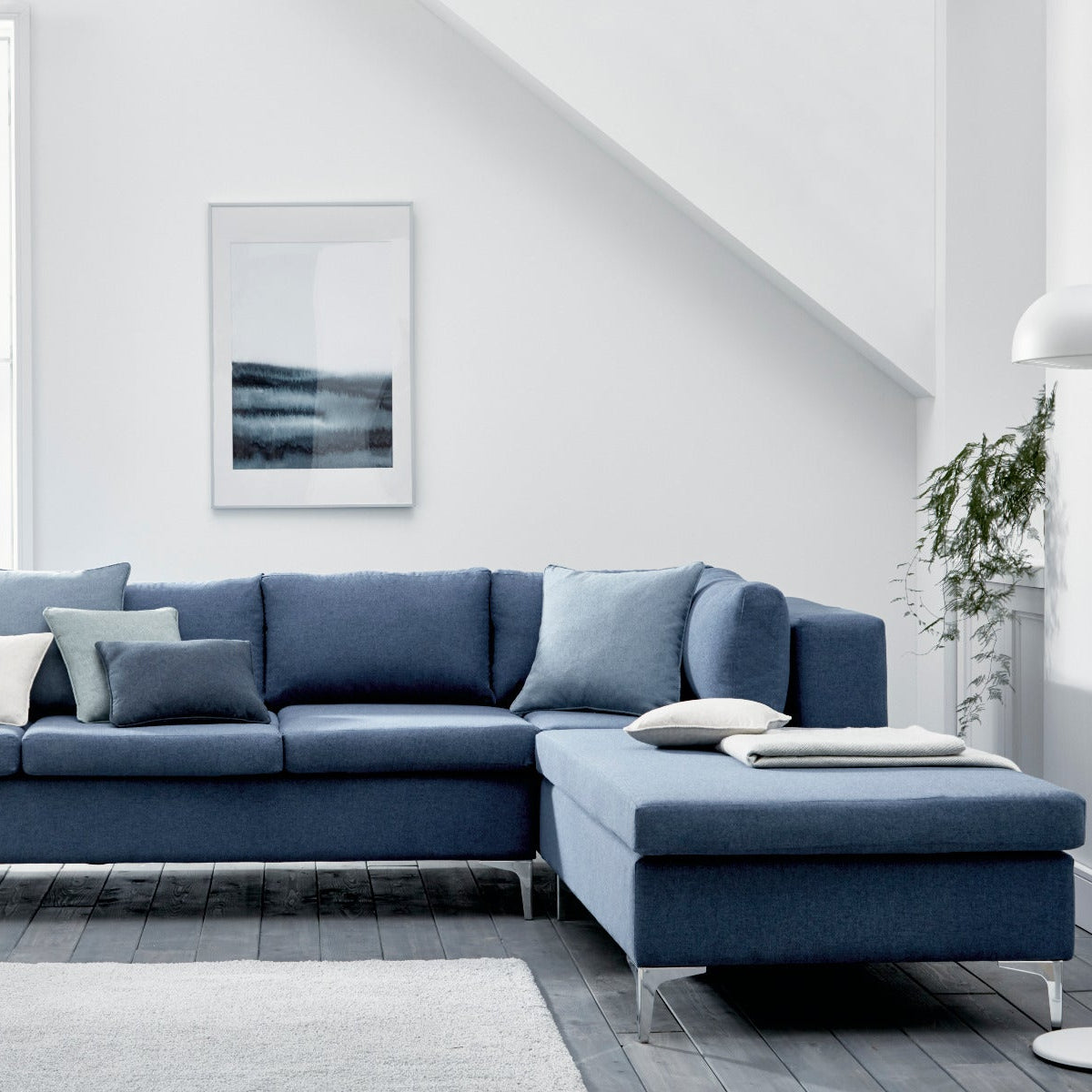 Blue sectional sofa in a modern living room with white walls and decor.