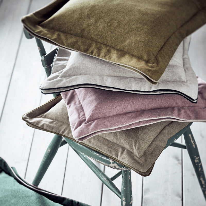 Stack of colorful cushions on a chair with a light background