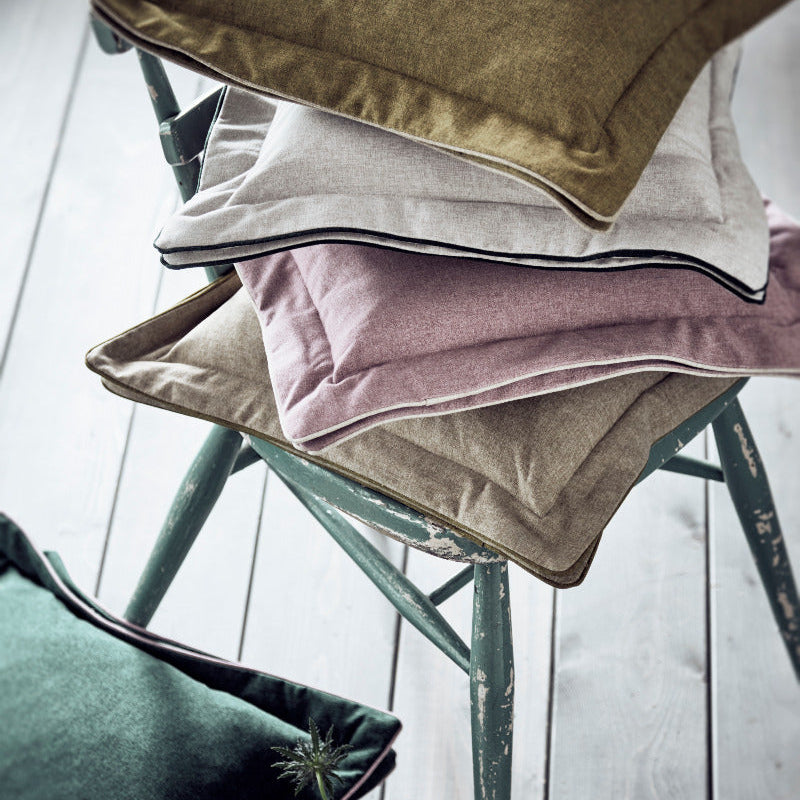 Stack of colorful cushions on a chair with a light background