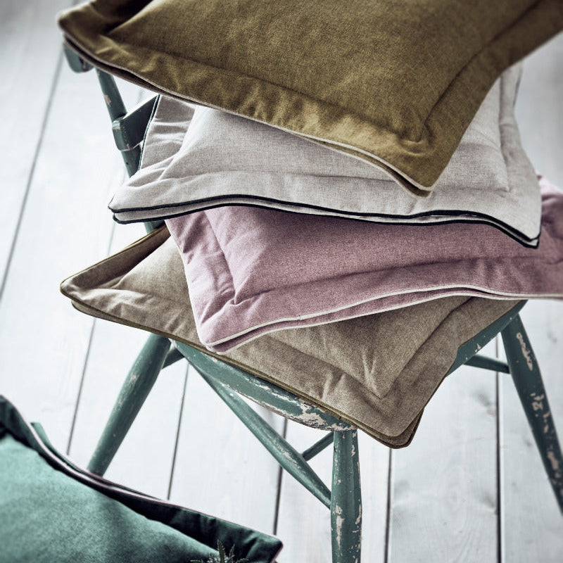 Stack of colorful cushions on a chair with a light background