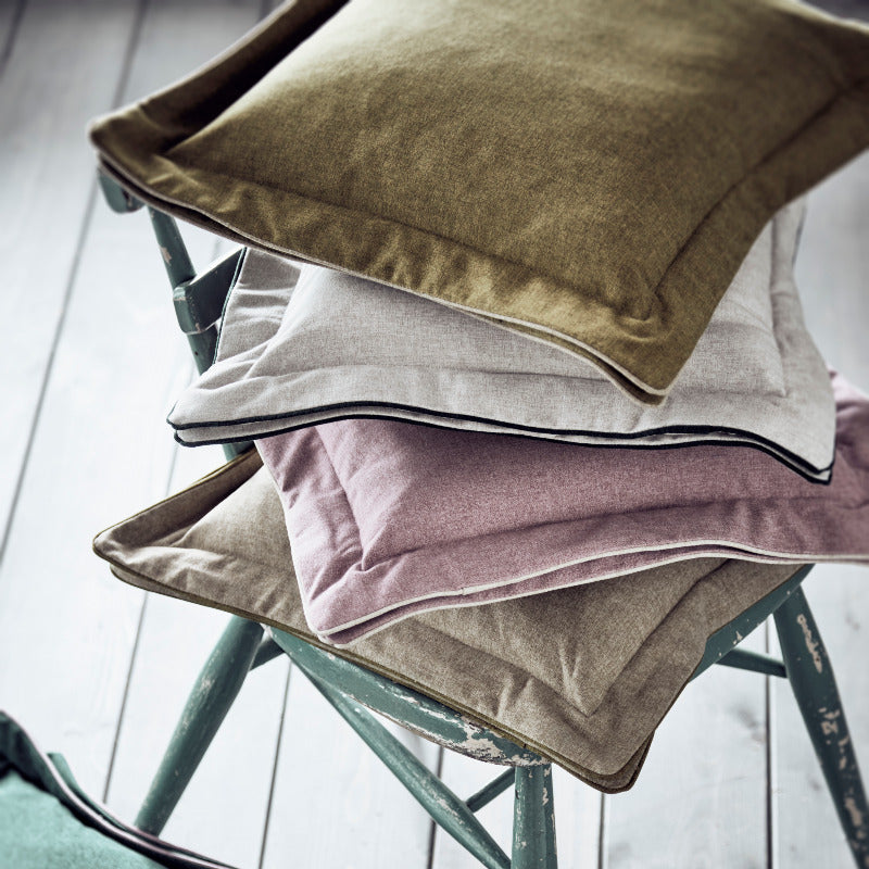 Stack of colorful pillows on a chair with a light background