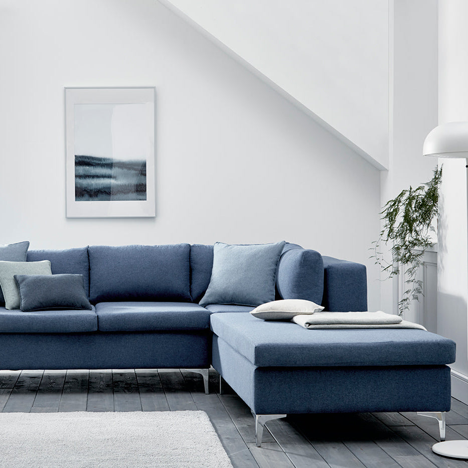 Blue sectional sofa in a modern living room with white walls and decor.