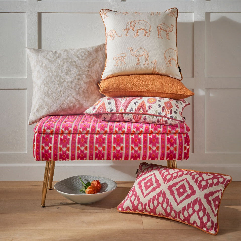 Decorative pillows on a small bench against a white paneled wall.