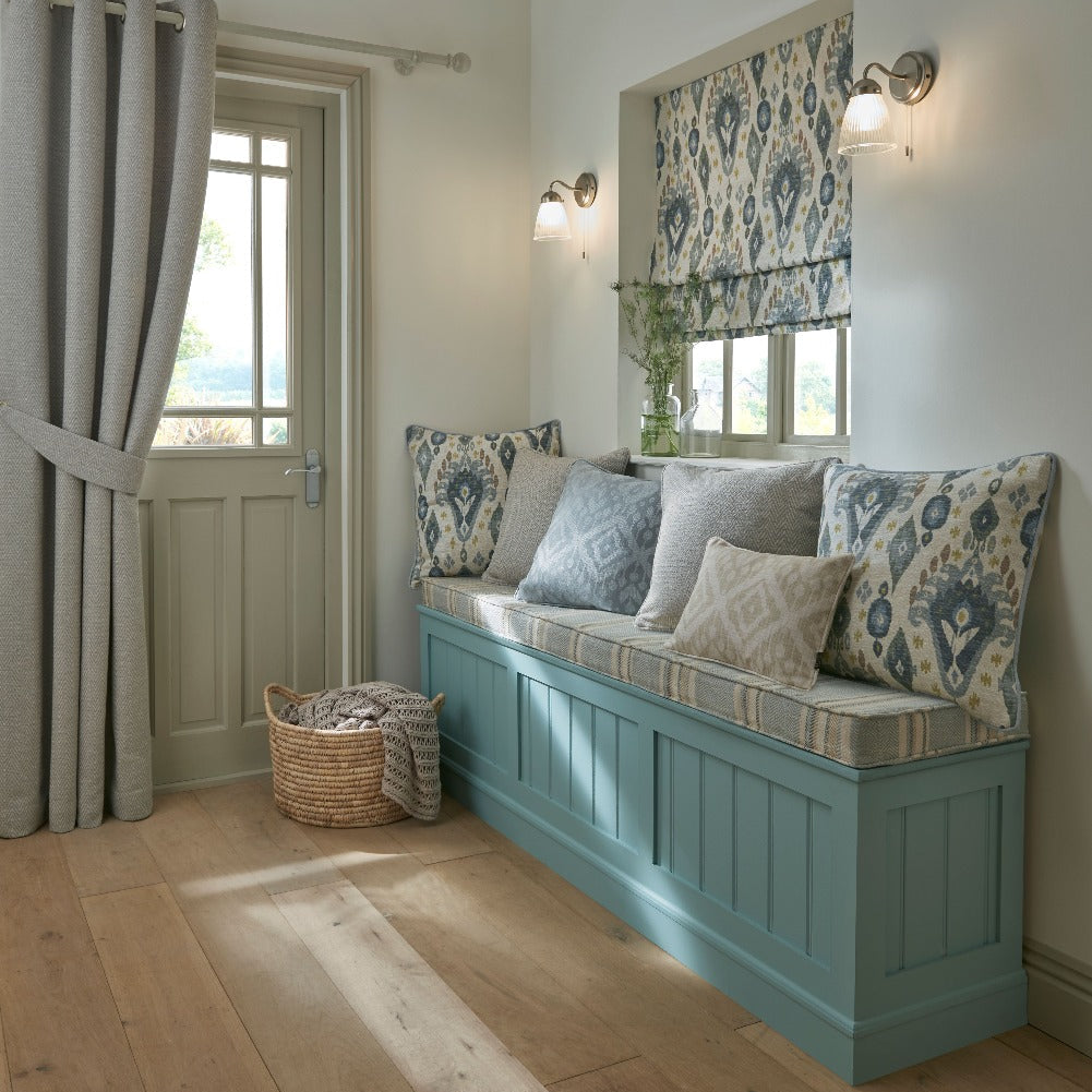 Nook with a blue bench, patterned cushions, and a basket on wooden flooring.