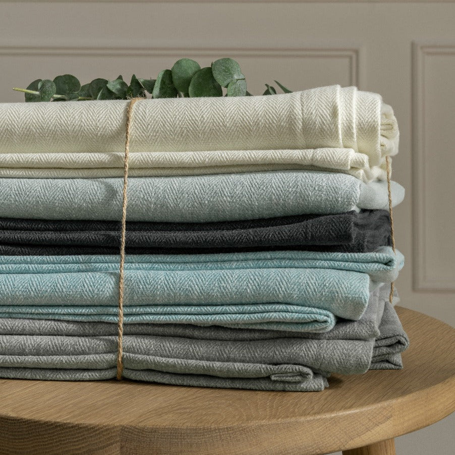 Stack of folded fabric pieces on a wooden table with a neutral background
