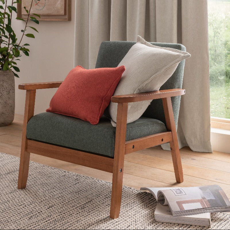 Wooden armchair with cushions in a room with curtains and a plant.