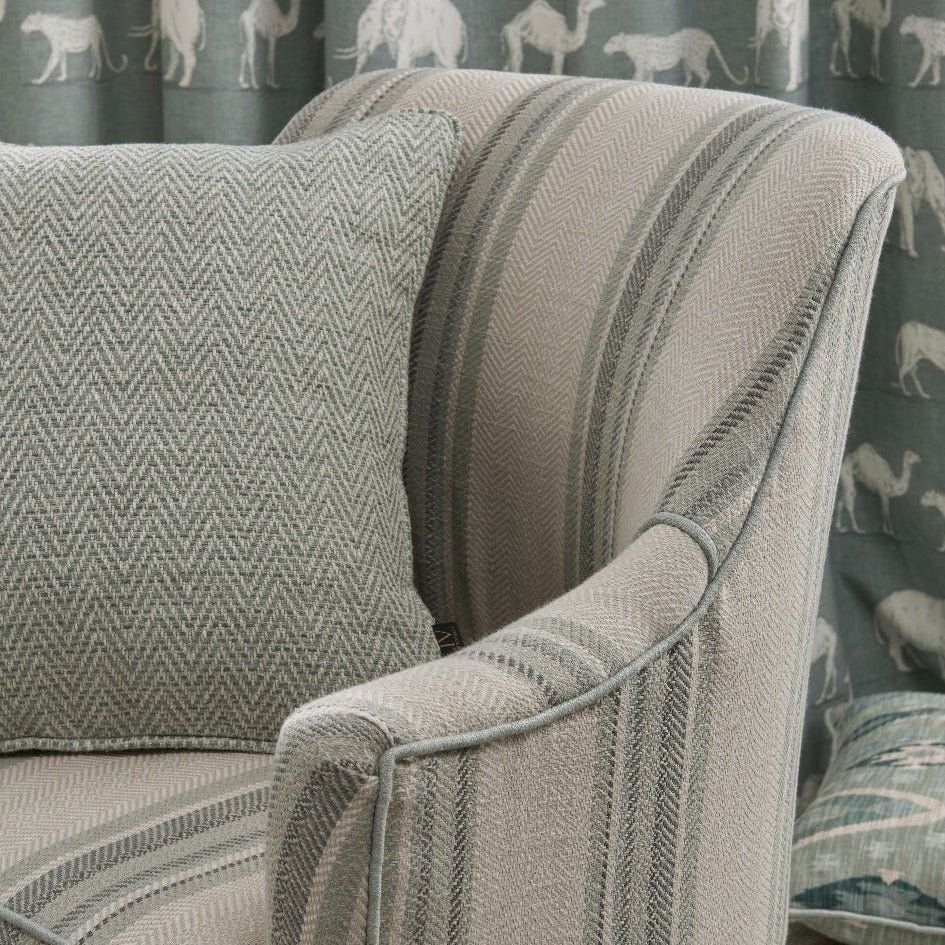 Patterned armchair with a decorative curtain featuring animal silhouettes in the background.