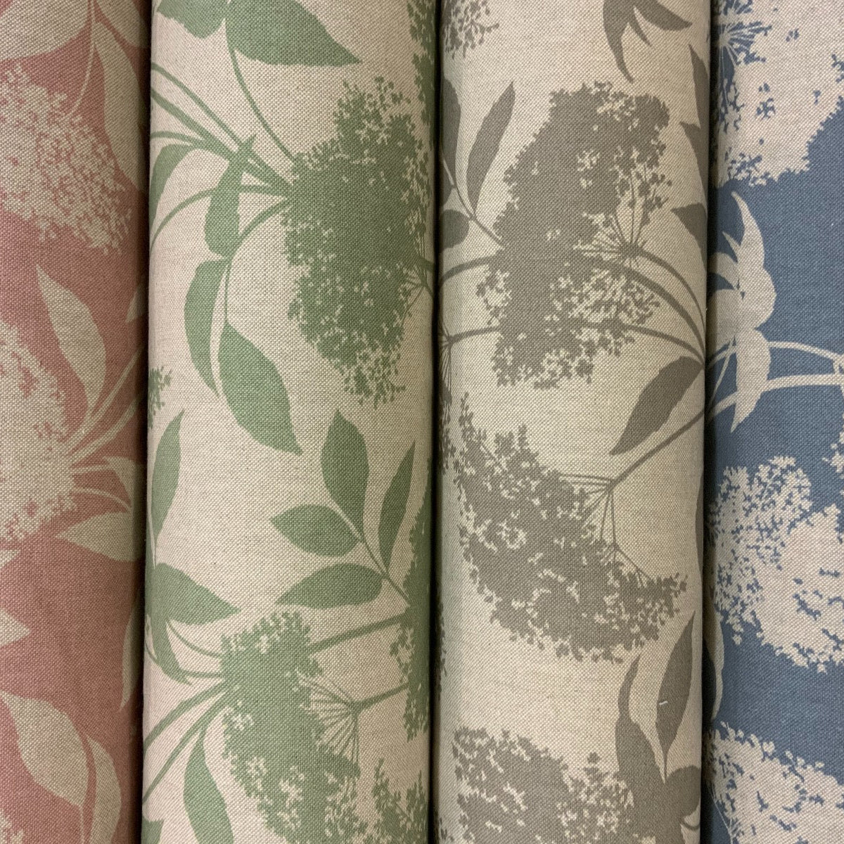 Five rolls of fabric with floral patterns in pink, green, gray, and blue.