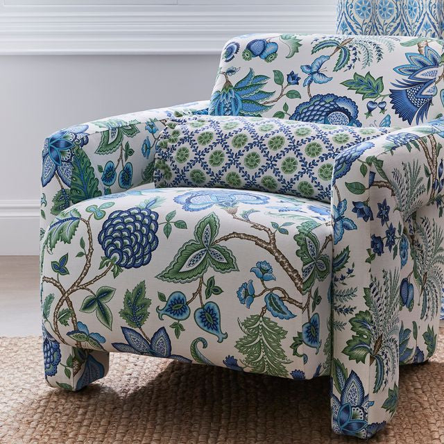 Floral patterned armchair in a room with a window and decorative wall.