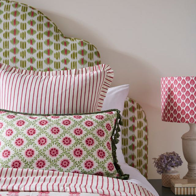 Patterned bedding with floral and striped designs on a bed and lamp.