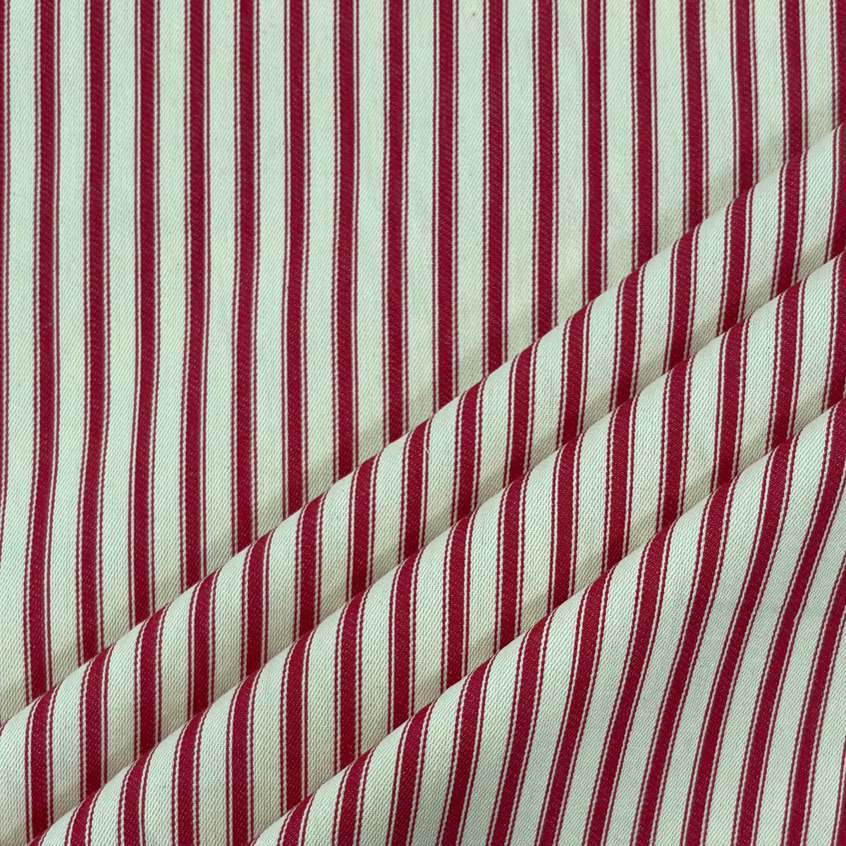 Classic red cotton ticking fabric with traditional stripe design folded at corner, ideal for cushions, tablecloths, table runners, lampshades, home furnishings and DIY craft projects. 