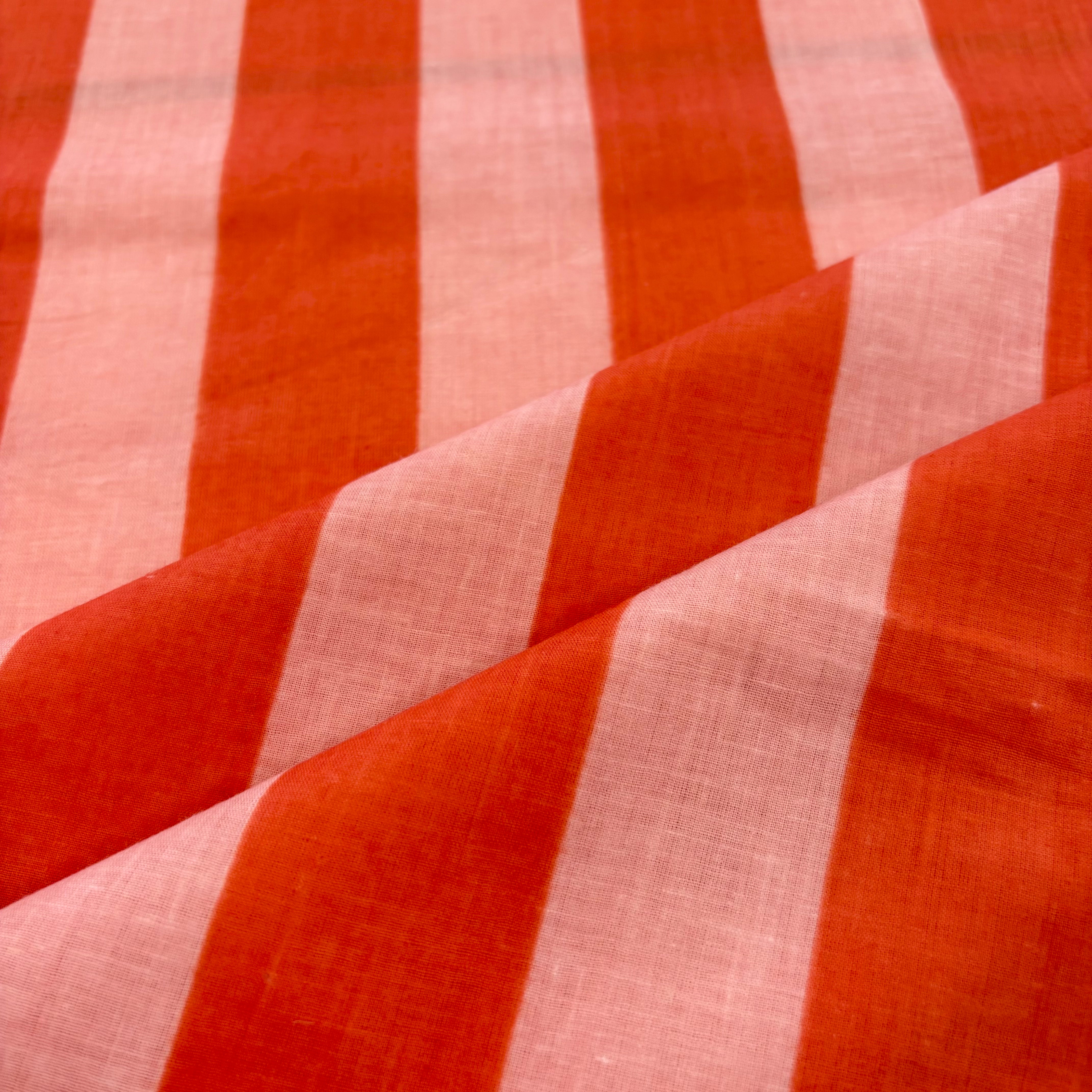 A close-up of a striped fabric with alternating wide bands of rust orange and light pink, showing a textured woven surface with soft diagonal folds.