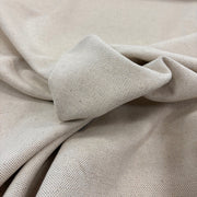 A close-up of linen woven fabric in a light neutral tone, showing the textile texture and soft folds.