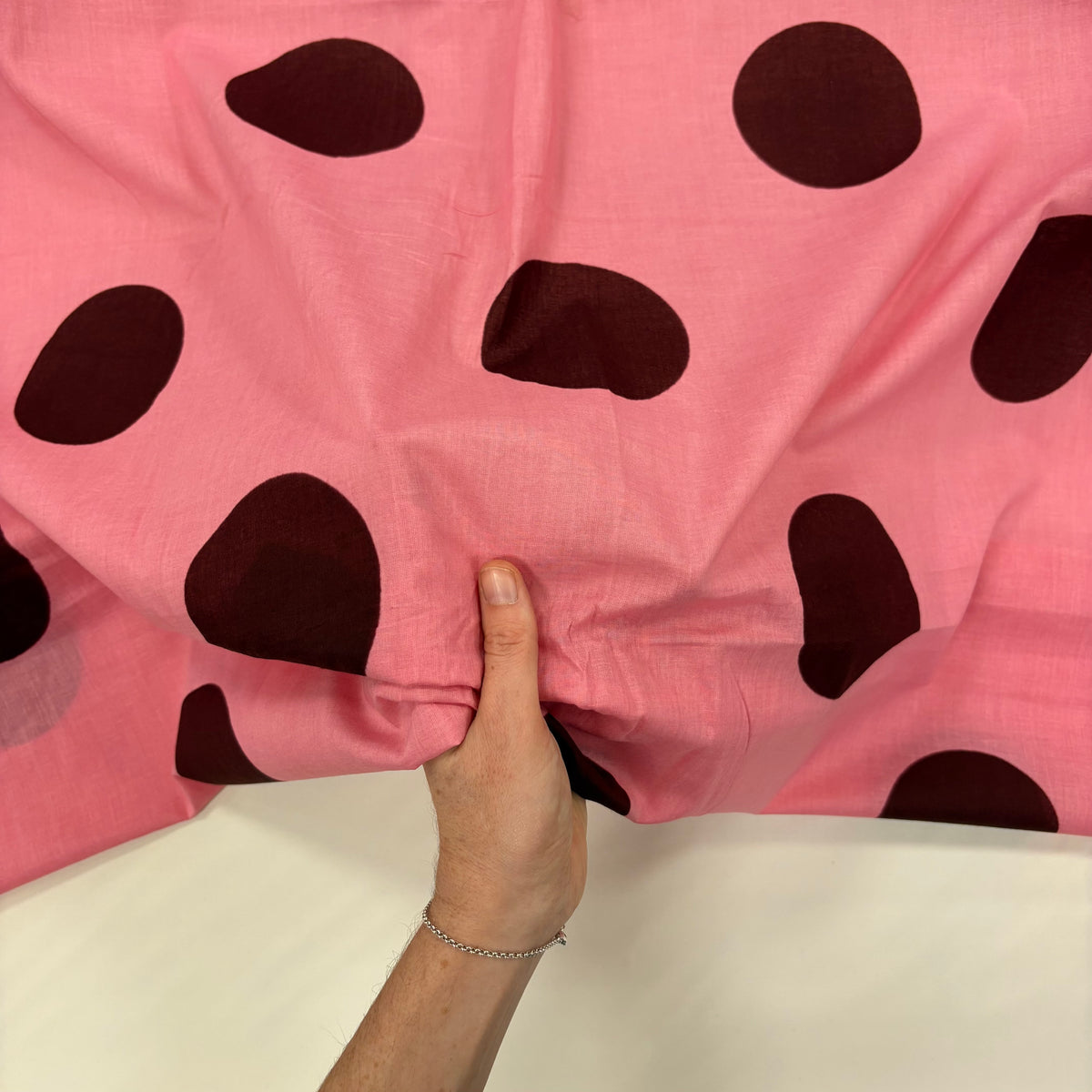 Pink Giant Spot Indian Print Cotton Fabric with hand for scale, lightweight 100gsm printed cotton for dressmaking, handmade gifts, crafts and soft furnishings, handcrafted using traditional Indian printing techniques.