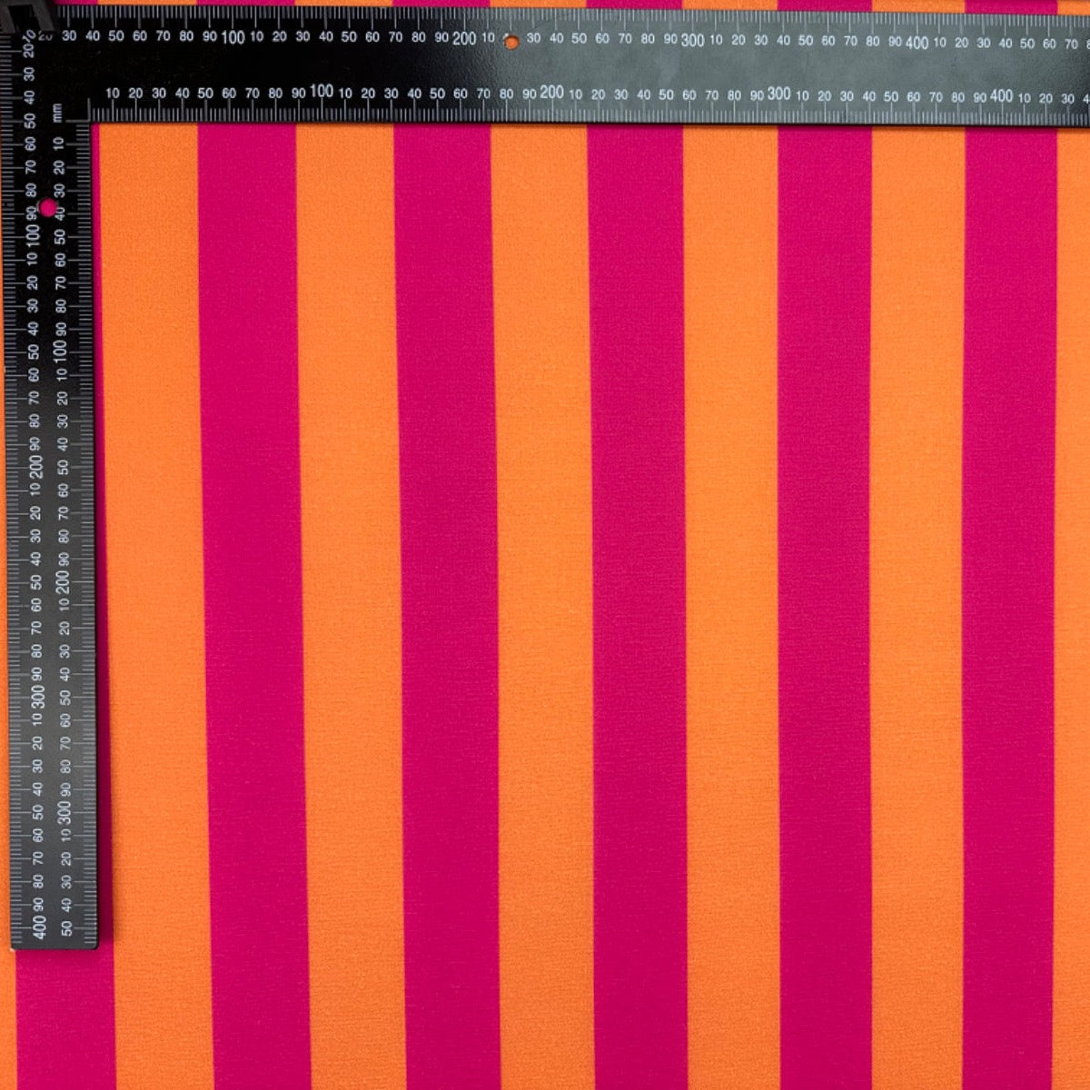 T545 Bold Candy Stripe Pink Fabric with pink and orange vertical stripes, measured by a ruler.