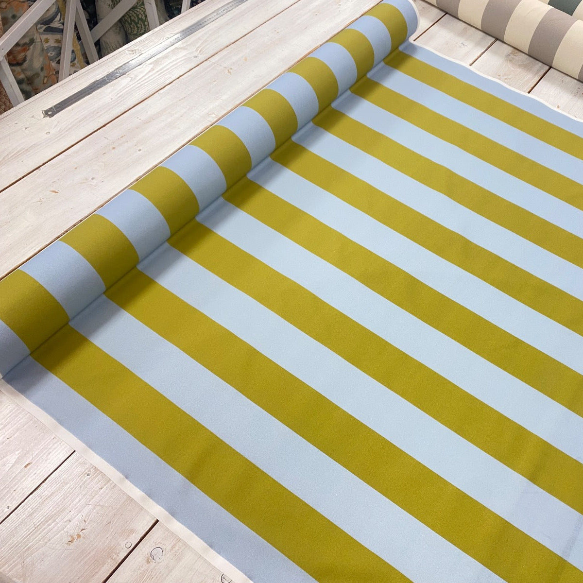 bold green and blue stripe cotton fabric roll laid on table
