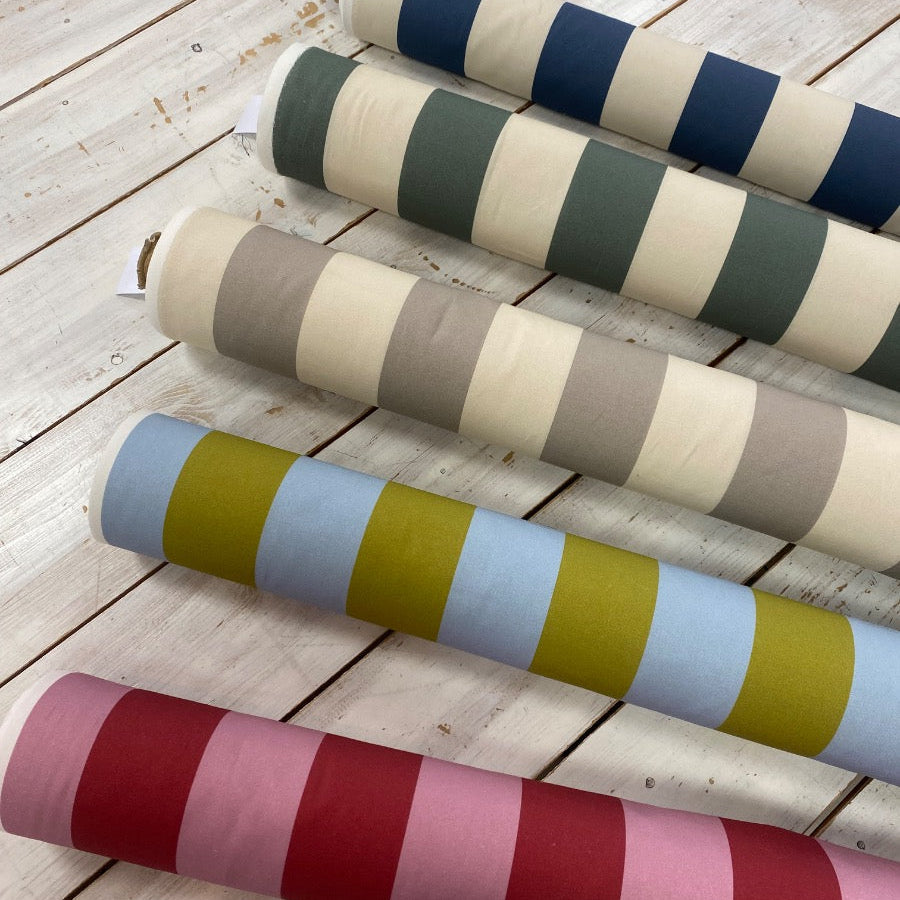 Rolls of fabric with striped patterns on a wooden surface