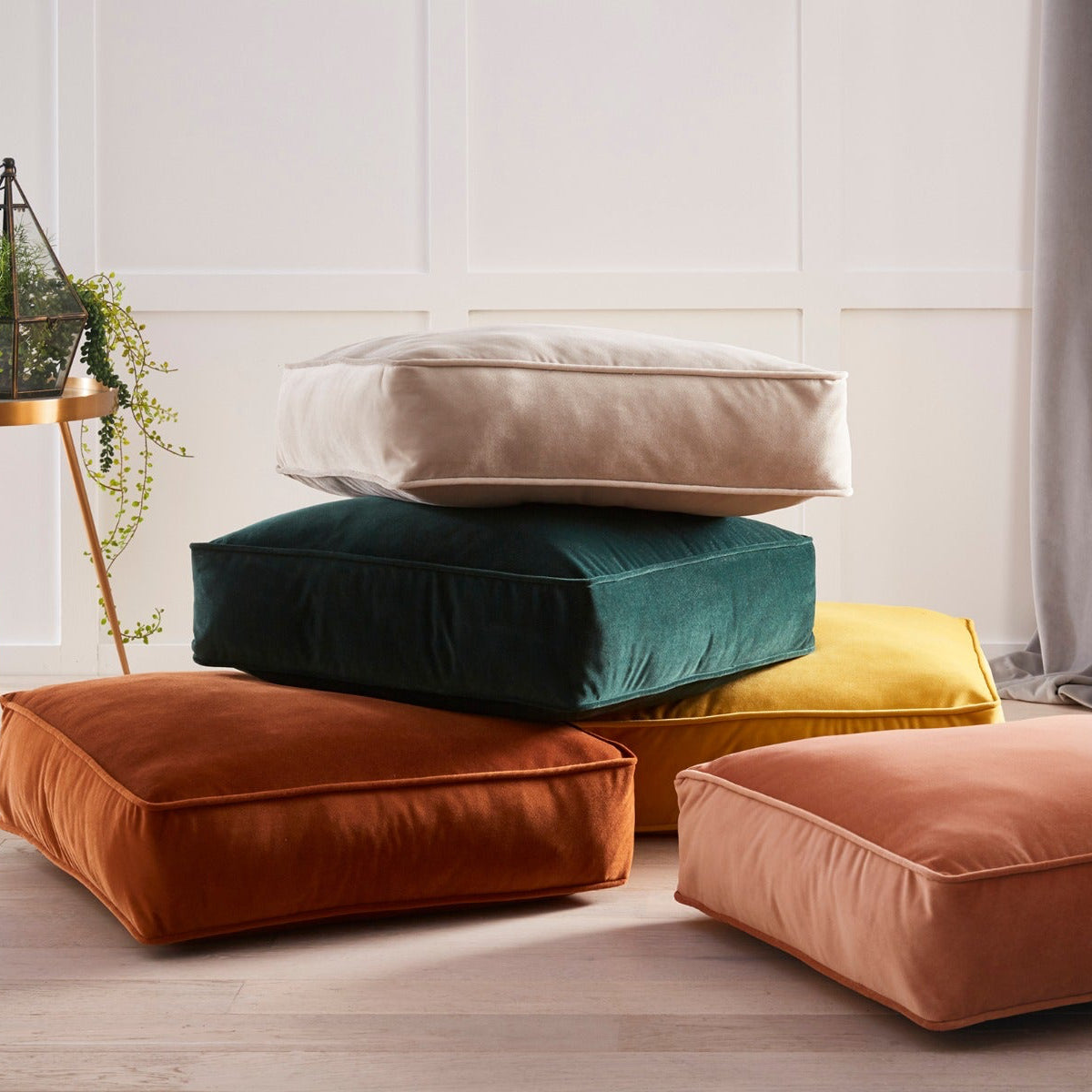 Stack of colorful cushions on a light wooden floor with a neutral wall background