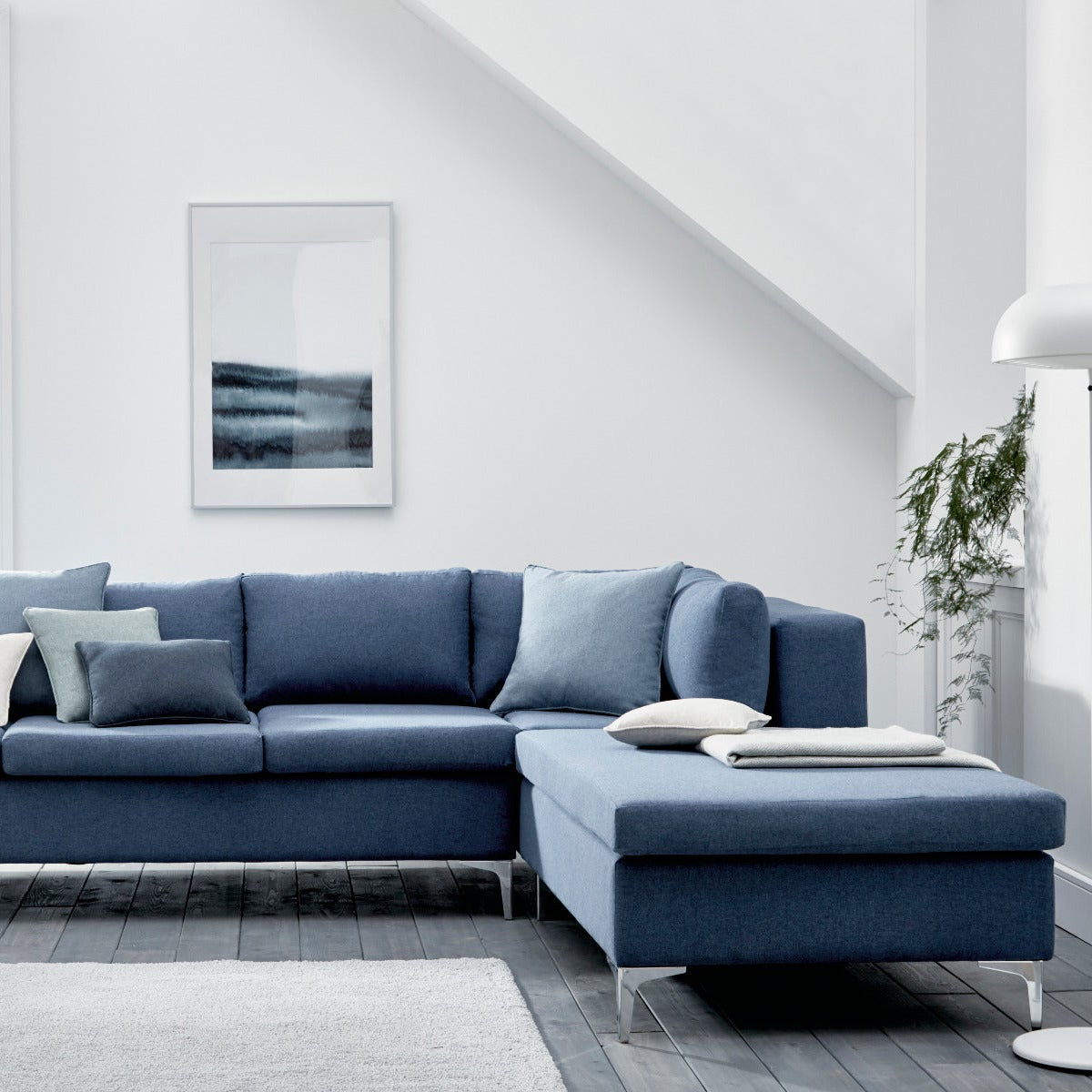 Blue sectional sofa in a modern living room with white walls and decor.