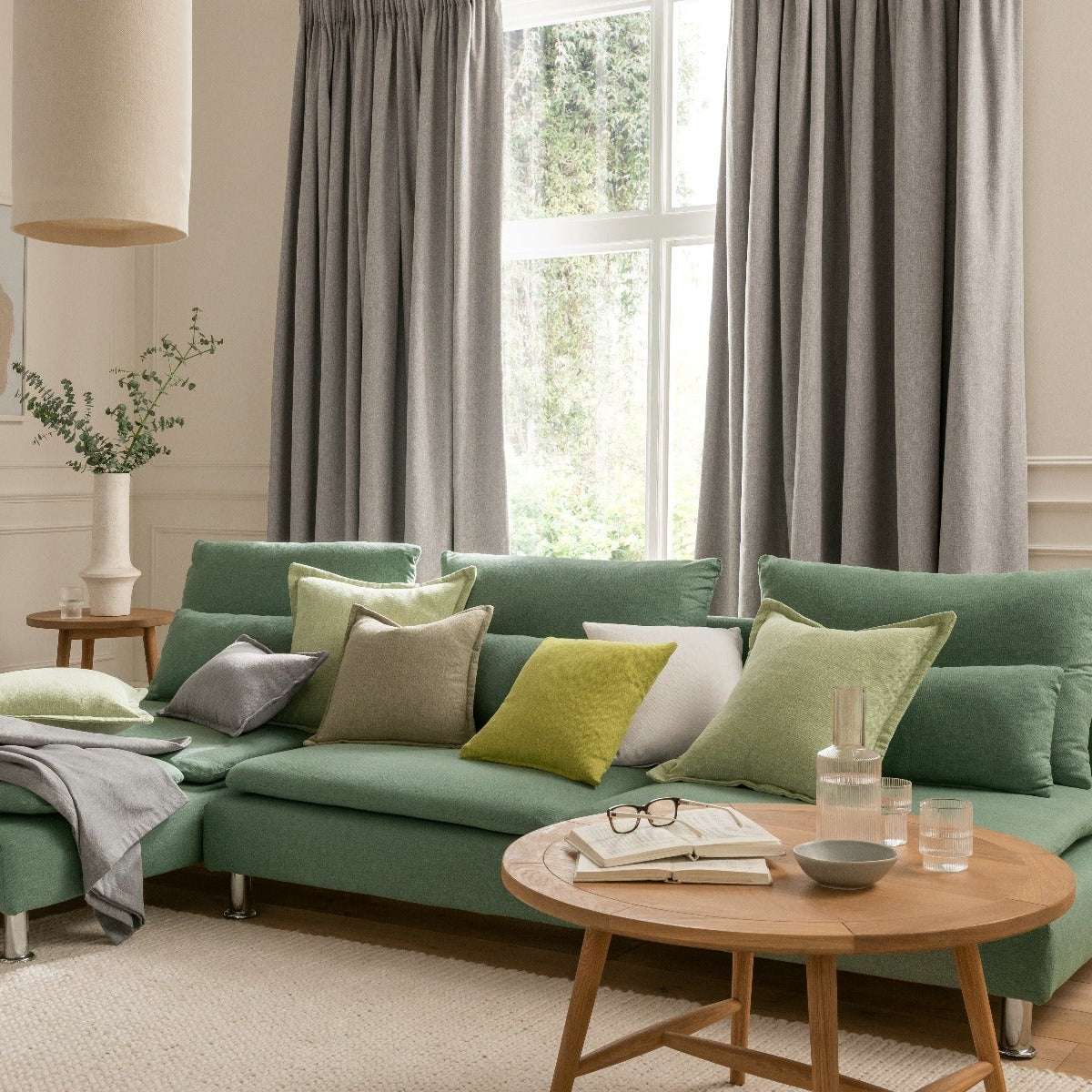 Green sectional sofa in a living room with a wooden coffee table and decorative items.