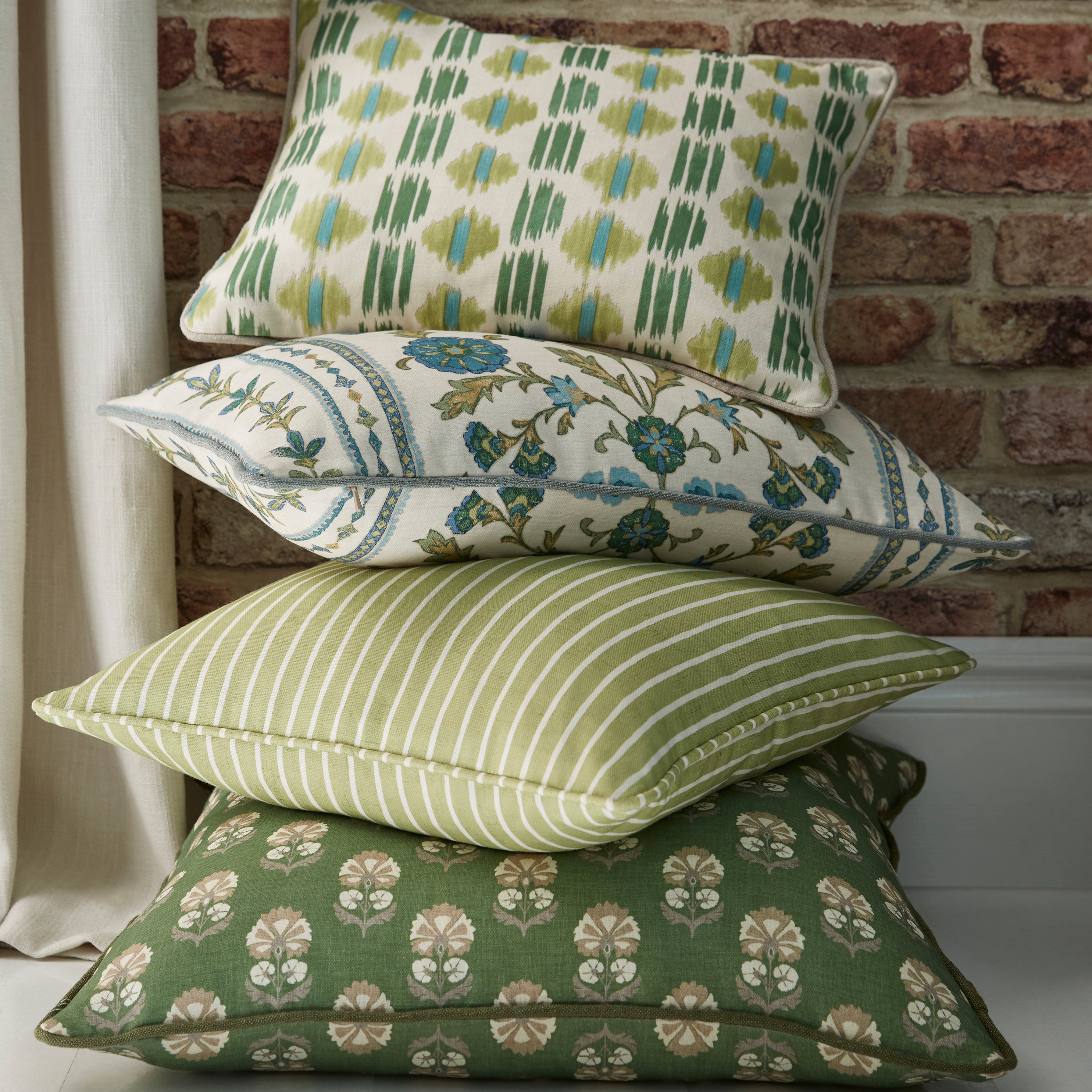 Stack of patterned pillows against a brick wall